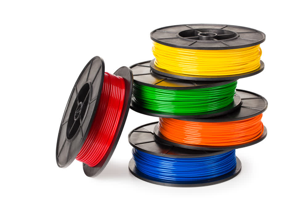 A stack of PLA filament spools in red, yellow, green, orange and blue